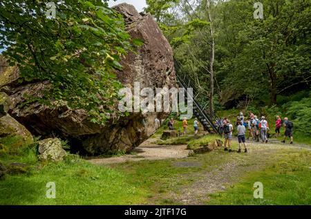 Menschen Touristen Besucher Wanderer am Bowder Stone Boulder Rock im Sommer Borrowdale Lake District National Park Cumbria England Großbritannien Stockfoto