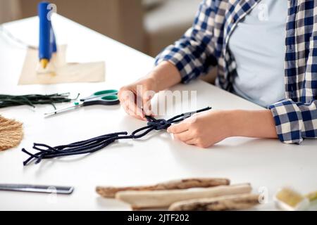 Frau, die Makrame macht und Schnüre verknotet Stockfoto