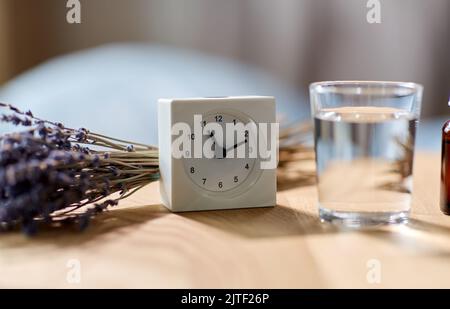 Wecker, Lavendelöl und ein Glas Wasser Stockfoto