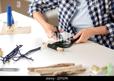 Frau schneidet Makramschnüre mit einer Schere Stockfoto