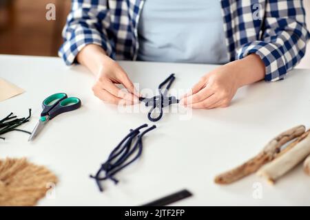 Frau, die Makrame macht und Schnüre verknotet Stockfoto