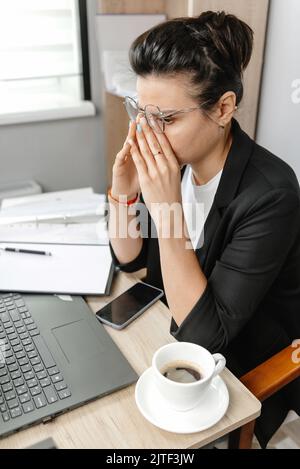 Eine junge und schöne Geschäftsfrau, müde von der Arbeit in einem Büro. Erschöpfte Geschäftsfrau bei der Arbeit im Büro Stockfoto