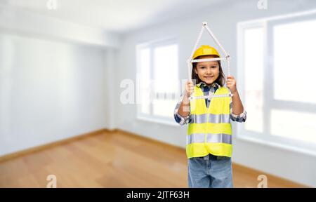 Kleines Mädchen im Helm mit Herrscher in Form von Haus Stockfoto