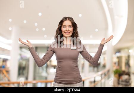 Glückliche weibliche Verkäuferin mit Namensschild Stockfoto