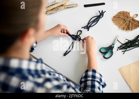 Frau, die Makrame macht und Schnüre verknotet Stockfoto