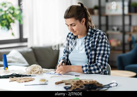 Frau schneidet Makramschnüre mit einer Schere Stockfoto