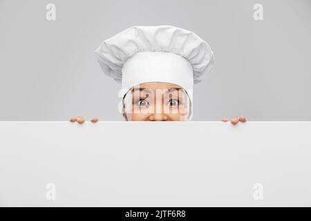 Die Köchin guckt hinter dem weißen Brett heraus Stockfoto
