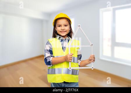 Kleines Mädchen im Helm mit Herrscher in Form von Haus Stockfoto