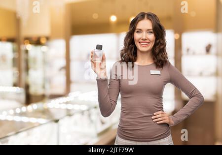 Glückliche weibliche Verkäuferin mit Parfüm Stockfoto