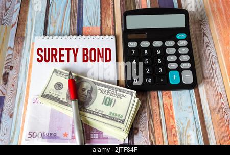 Geschäfts- und Finanzkonzept. Auf dem Tisch steht ein Rechner, Geldscheine in Dollar und Euro sowie ein Notizblock mit der Inschrift- BÜRGSCHAFT Stockfoto