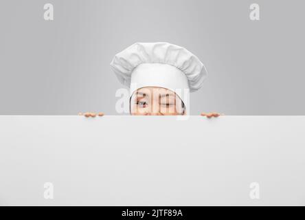 Die Köchin guckt hinter dem weißen Brett heraus Stockfoto