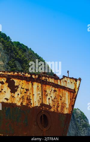 Tagesansicht eines verlassenen, rostigen Schiffswracks mit einem sichtbaren Bug auf der Insel Zakynthos in Griechenland vor blauem Himmel. Stockfoto