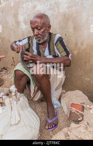 TADJOURA, DSCHIBUTI - 20. APRIL 2019: Schuhmailor auf einem Markt in Tadjoura, Dschibuti Stockfoto