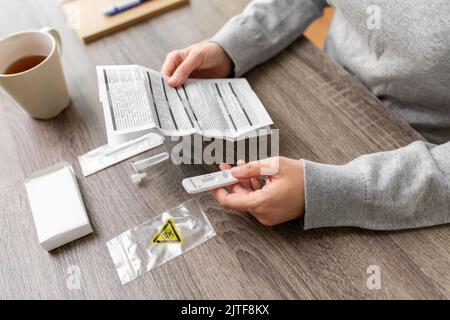 Frau liest zuhause das Coronavirus-Testhandbuch Stockfoto