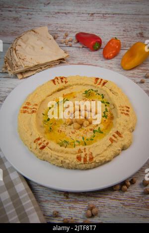 Hausgemachter Hummus mit Tahini-Teller mit Olivenöl und Paprika und Pita isoliert auf braunem Hintergrund Stockfoto