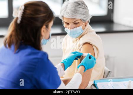 Krankenschwester, die eine geimpfte Frau mit einem medizinischen Pflaster bewirbt Stockfoto