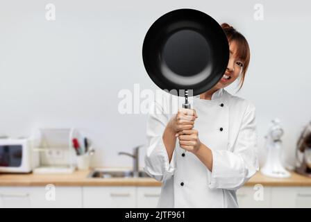Der Koch guckt hinter der Bratpfanne in die Küche Stockfoto