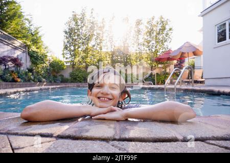Porträt eines lächelnden Jungen (10-11) im Garten-Swimmingpool Stockfoto