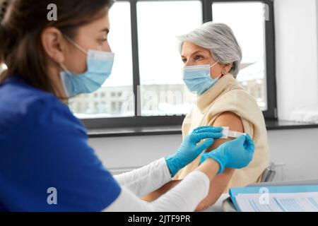 Krankenschwester, die eine geimpfte Frau mit einem medizinischen Pflaster bewirbt Stockfoto
