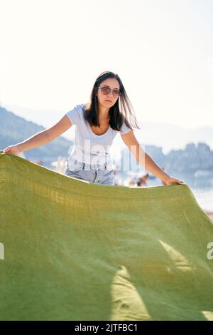Junge Frau legt eine Decke auf den Kiesstrand Stockfoto