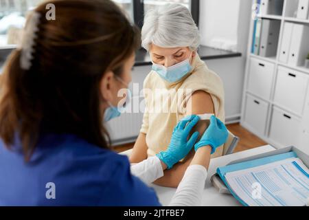 Krankenschwester, die eine geimpfte Frau mit einem medizinischen Pflaster bewirbt Stockfoto