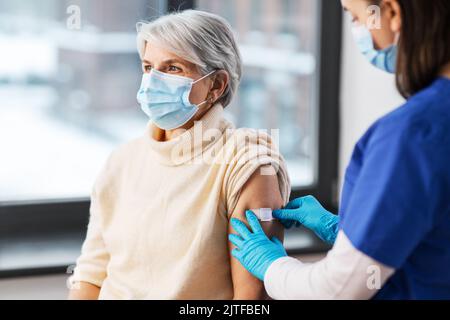 Krankenschwester, die eine geimpfte Frau mit einem medizinischen Pflaster bewirbt Stockfoto
