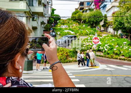 Eine Dame fotografiert die Lombard Street in San Francisco, Kalifornien, mit ihrem Mobiltelefon. Stockfoto