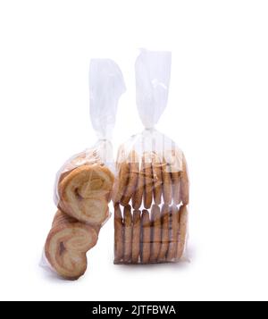 Herzförmiges Blätterteig, verpackt in Plastiktüten, isoliert auf weißem Hintergrund. Palmier Cookies. Stockfoto