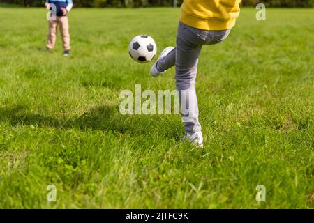 Fröhliche kleine Jungs mit Fußball spielen im Park Stockfoto