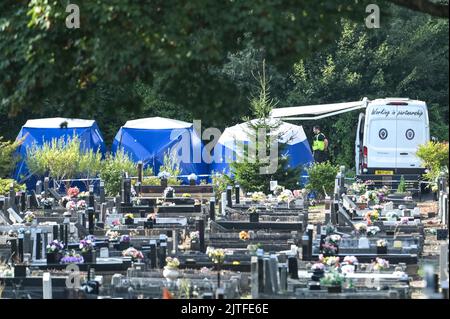 Tipton Cemetery, West Midds August 30. 2022 - die Polizei durchsiebt die Erde von einem sprung, wo am Samstag, dem 27. August, menschliche Überreste auf dem Tipton Cemetery, West Midlands, gefunden wurden. Drei blaue forensische Zelte waren zu sehen, zusammen mit mehreren Polizeiwagen, Forensik-Beamten in weißen Anzügen und einer Kordon am Ende des Friedhofs, in der Nähe des Spielplatzes der Akademie Q3. Ein Sprecher der Polizei von West Midlands sagte: ‘Wir untersuchen, nachdem am Samstagabend (27. August) auf dem Tipton Cemetery in der Alexandra Road menschliche Überreste gefunden wurden. Das Gebiet wurde für weitere Durchsuchungen abgesperrt Stockfoto