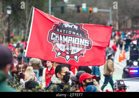 ATHEN, GA - 15. JANUAR 2022: Ein Mann winkt bei der UGA-Siegesparade am 15. Januar 2022 in Athen, GA, mit einer Flagge der College-Fußballnationalmeisterschaft. Stockfoto