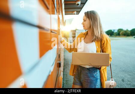 Frau, die per automatisiertem Postterminal Post versendet. Stockfoto
