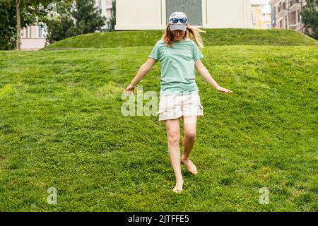 Glückliche junge Frau barfuß auf grünem Rasen spazieren und den warmen Regen im Sommer genießen und das Naturgefühl genießen Stockfoto