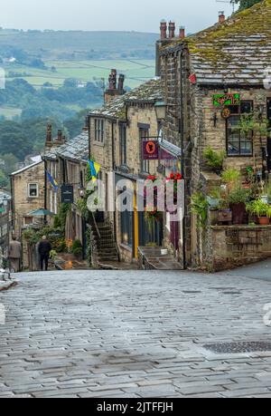 Hütten, Geschäfte und Cafés an der Haworth Main Street in Yorkshire. Haworht ist berühmt dafür, die Heimat der Bronte-Schwestern zu sein. Stockfoto