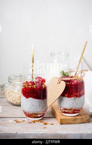 Zwei Gläser Chia Pudding mit Müsli und Himbeeren. Stockfoto