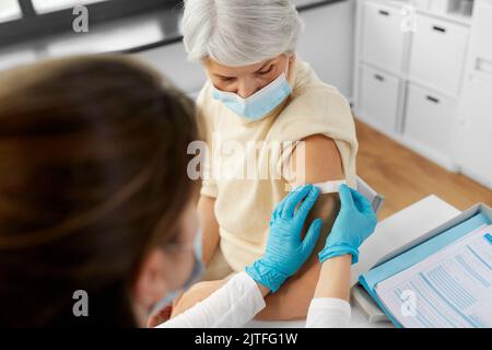 Krankenschwester, die eine geimpfte Frau mit einem medizinischen Pflaster bewirbt Stockfoto