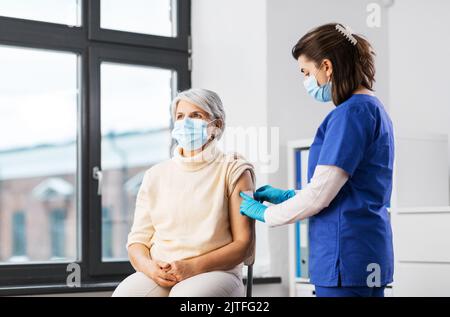 Krankenschwester, die eine geimpfte Frau mit einem medizinischen Pflaster bewirbt Stockfoto