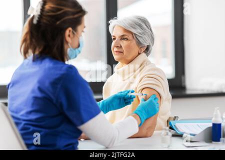 Krankenschwester mit Spritze, die der Frau Injektion macht Stockfoto