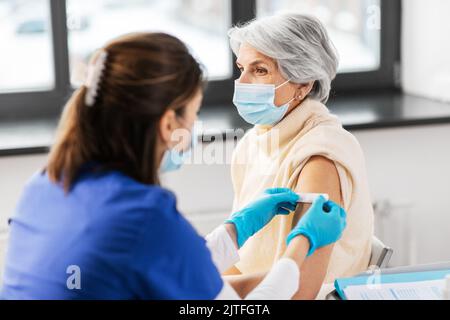 Krankenschwester, die eine geimpfte Frau mit einem medizinischen Pflaster bewirbt Stockfoto