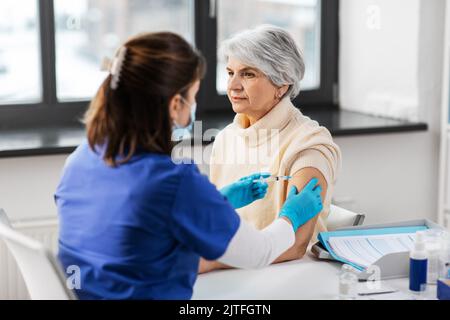 Krankenschwester mit Spritze, die der Frau Injektion macht Stockfoto