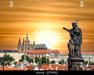 Statue eines heiligen auf der Karlsbrücke in Richtung Prager Burg in der Tschechischen Republik. Wunderschöne Sonnenuntergangsszene in Prag. Stockfoto