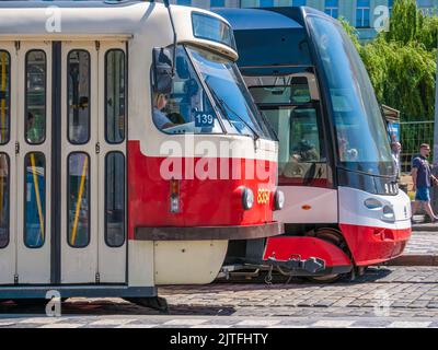 Prag, Tschechische Republik - Juni 2022: Alte alte rote Straßenbahn neben einer neuen modernen Straßenbahn am Bahnhof in Prag Stockfoto