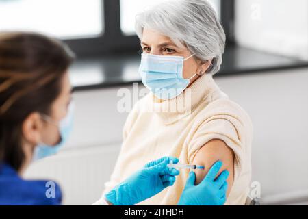 Krankenschwester mit Spritze, die der Frau Injektion macht Stockfoto