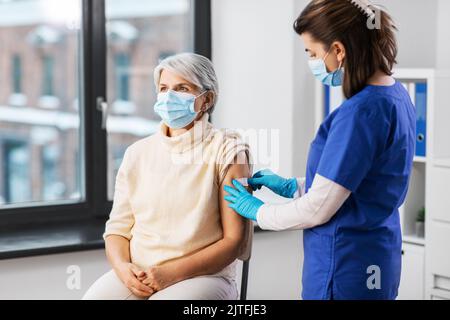 Krankenschwester, die eine geimpfte Frau mit einem medizinischen Pflaster bewirbt Stockfoto