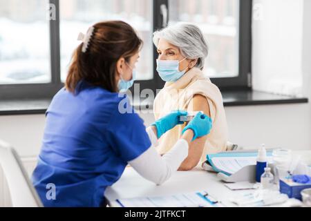 Krankenschwester, die eine geimpfte Frau mit einem medizinischen Pflaster bewirbt Stockfoto