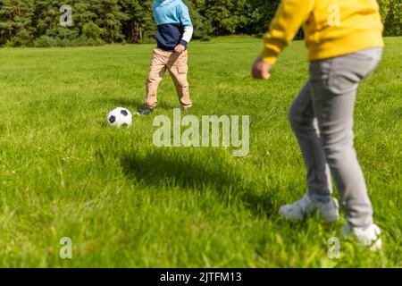 Fröhliche kleine Jungs mit Fußball spielen im Park Stockfoto