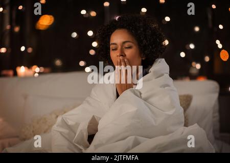 Gähnende Frau in Bettdecke in der Nacht eingewickelt Stockfoto