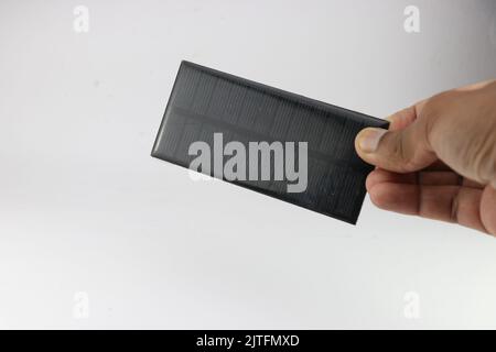 Solarpanel oder kleine Solarzelle in der Hand gehalten aus Silizium auf weißem Hintergrund Stockfoto