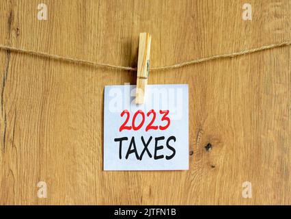 2023 Steuern Neujahr Symbol. Weißes Papier mit Worten 2023 Steuern, Clip auf Holzlasche. Schöner Holzhintergrund. Geschäft und 2023 Steuern neu yea Stockfoto