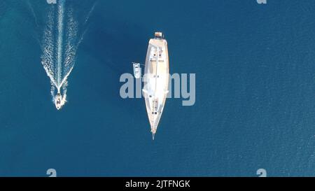 Eine Luftdrohne von einer privaten Yacht und einem kleinen Motorboot, das an sonnigen Tagen auf blauem Ozean segelt Stockfoto